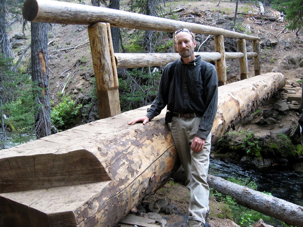 John Schubert with one of his traditional joinery bridges along the North Fork Trail. Photo by Ellen Santasiero