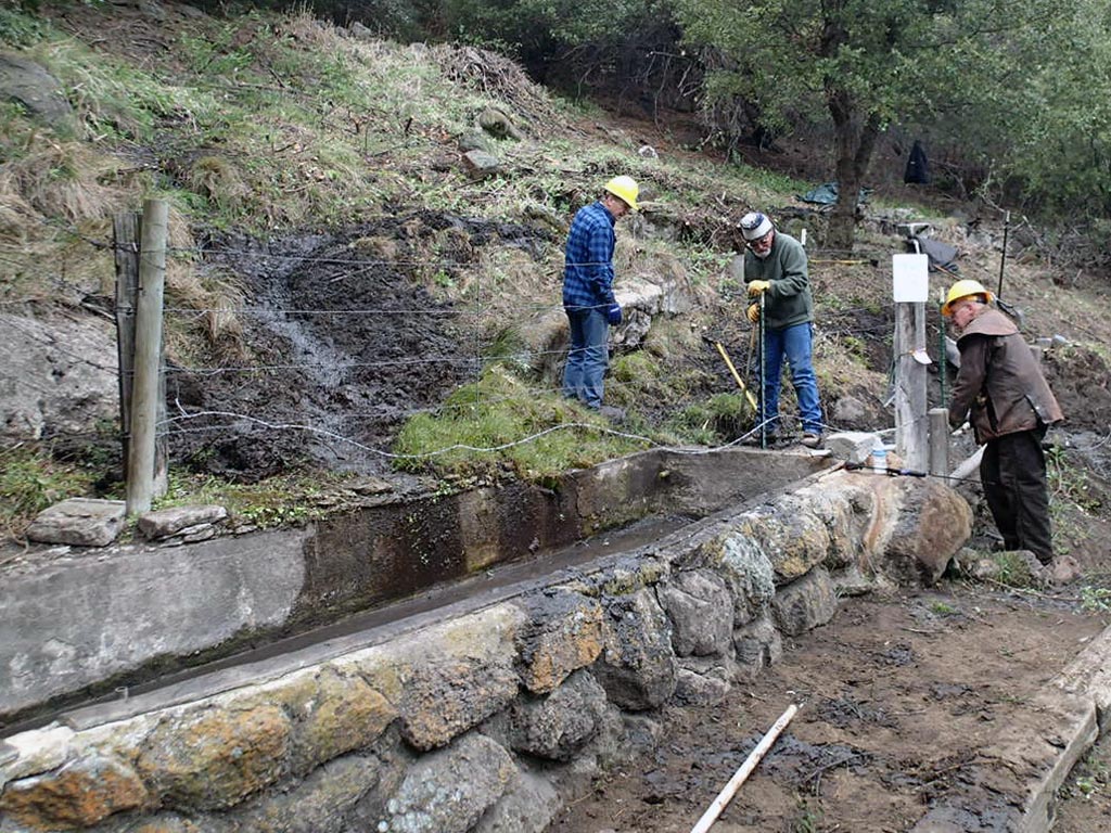 Volunteers dig out new channels for Golden Oaks Spring after having cleared the slope above of brush.
