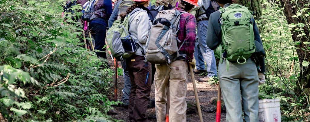 New volunteers listen in at a Trail Skills College class teaching tread reconstruction to new volunteers. Photo: Gray Feather Photography.