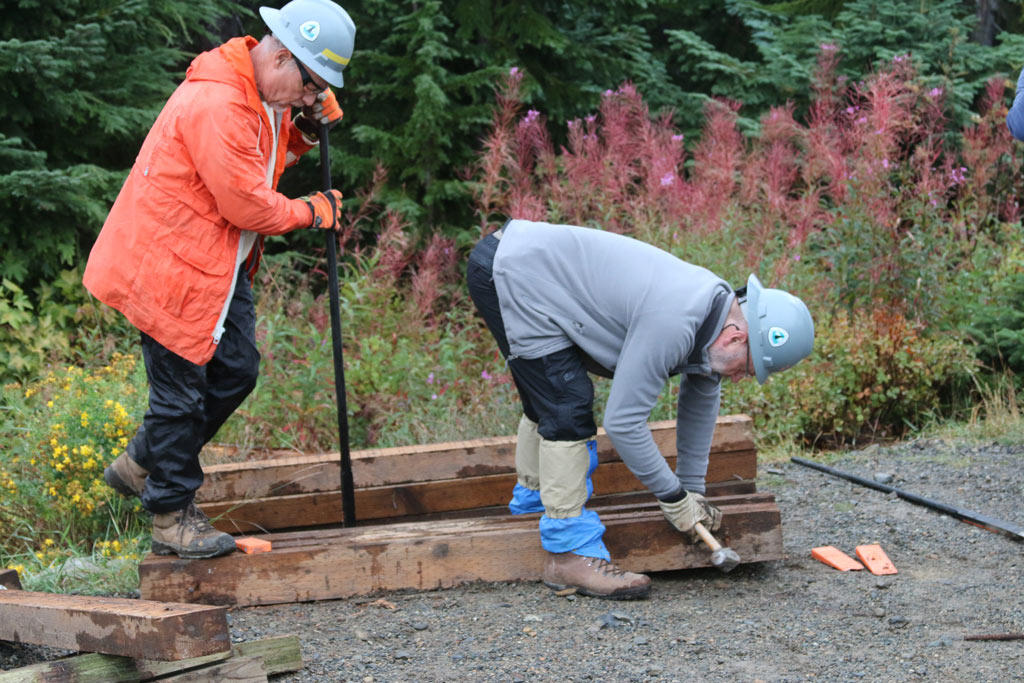 Volunteers Jack Jensen and Paul Gardiner work to separate timbers that will be used to construct new turnpikes.