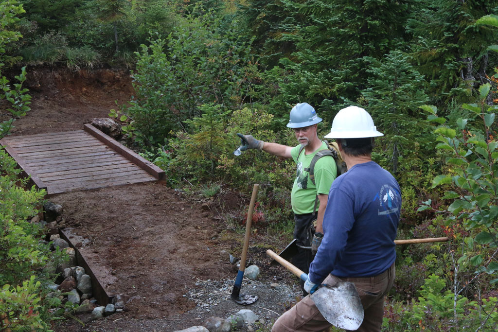 Crew Leader Barry Teschlog and PCTA Regional Representative Bill Hawley inspect safety improvements to a creek crossing.