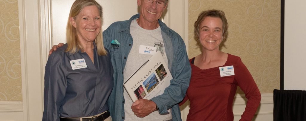 Liz Bergeron, left, and Regional Representative Dana Hendricks, right, congratulate Ed Wilson on being named Trail Maintainer of the Year for the Columbia Cascades region. Photo by Frank Gorshe.