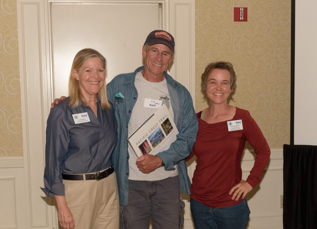 Liz Bergeron, left, and Regional Representative Dana Hendricks, right, congratulate Ed Wilson on being named Trail Maintainer of the Year for the Columbia Cascades region. Photo by Frank Gorshe.