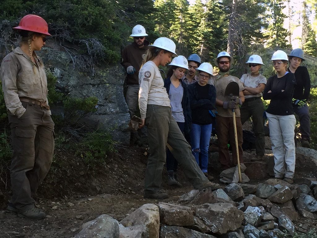 Learning how to build a rock wall on a trail. ACE corp crew members teach PCTA volunteers about dry masonry