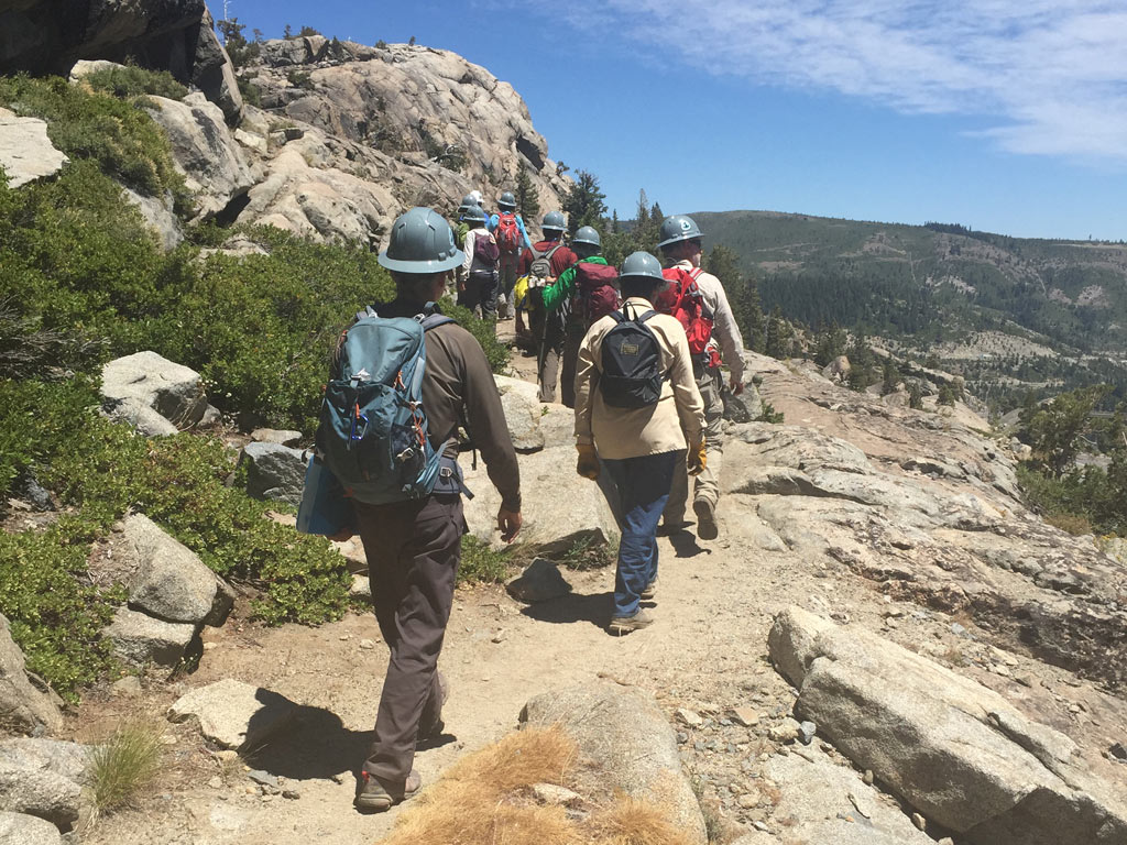 Students hike into their Intro to Trail Maintenance class site during the 2016 Tahoe Trail Skills College – by Bill Cunningham