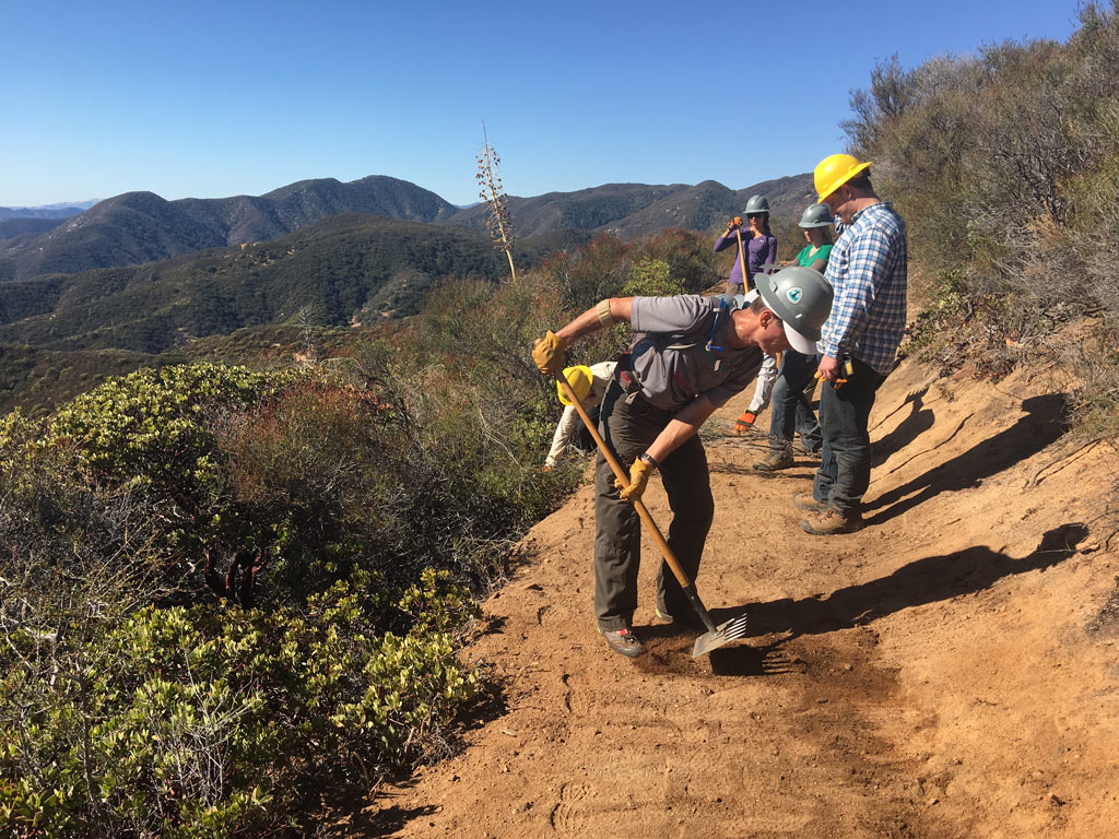 Volunteers perform final touches after the trail machine cuts through the hillside. Photo by Niki Forgues