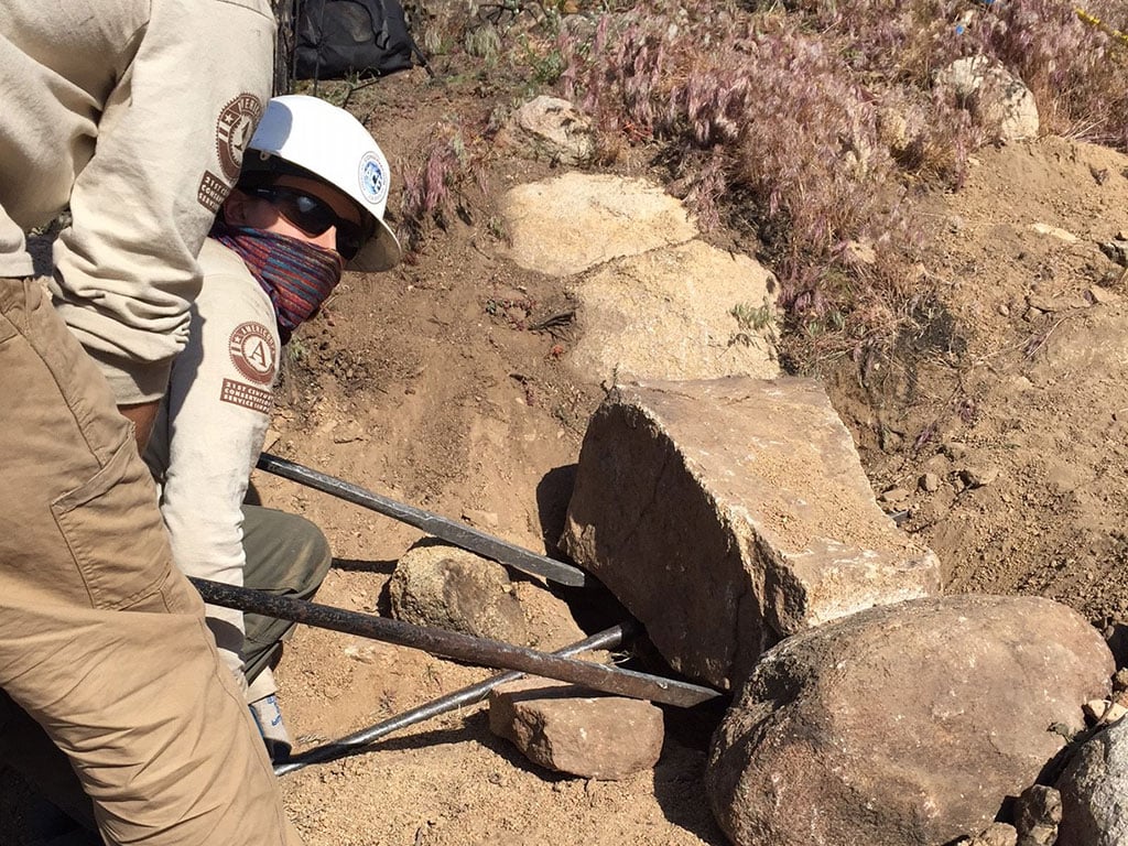 NCCC trail crew uses a rock bar to move a rock