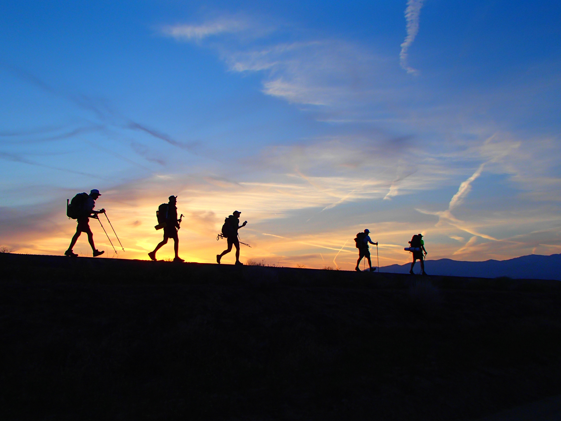 Sunset behind hikers walking along the top of the Los Angeles Aqueduct in the Mojave Desert. Photo by Clayton Feider-Sullivan.