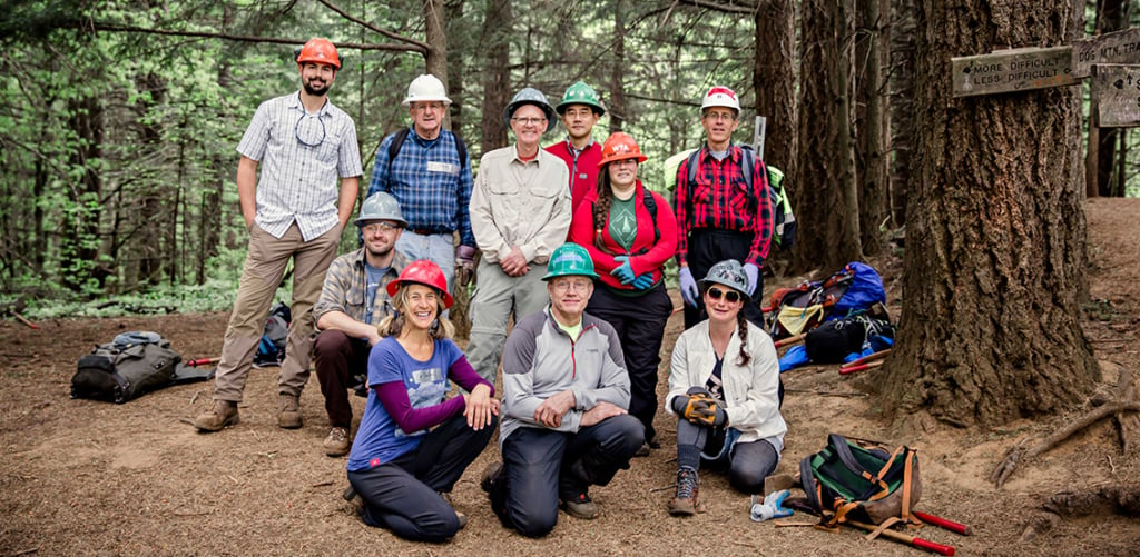 A trail crew poses near the trailhead with their gear.