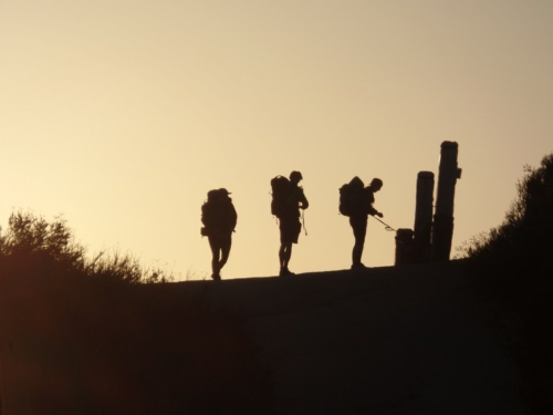 Three hikers silhouetted against the sun at the PCT Southern Terminus